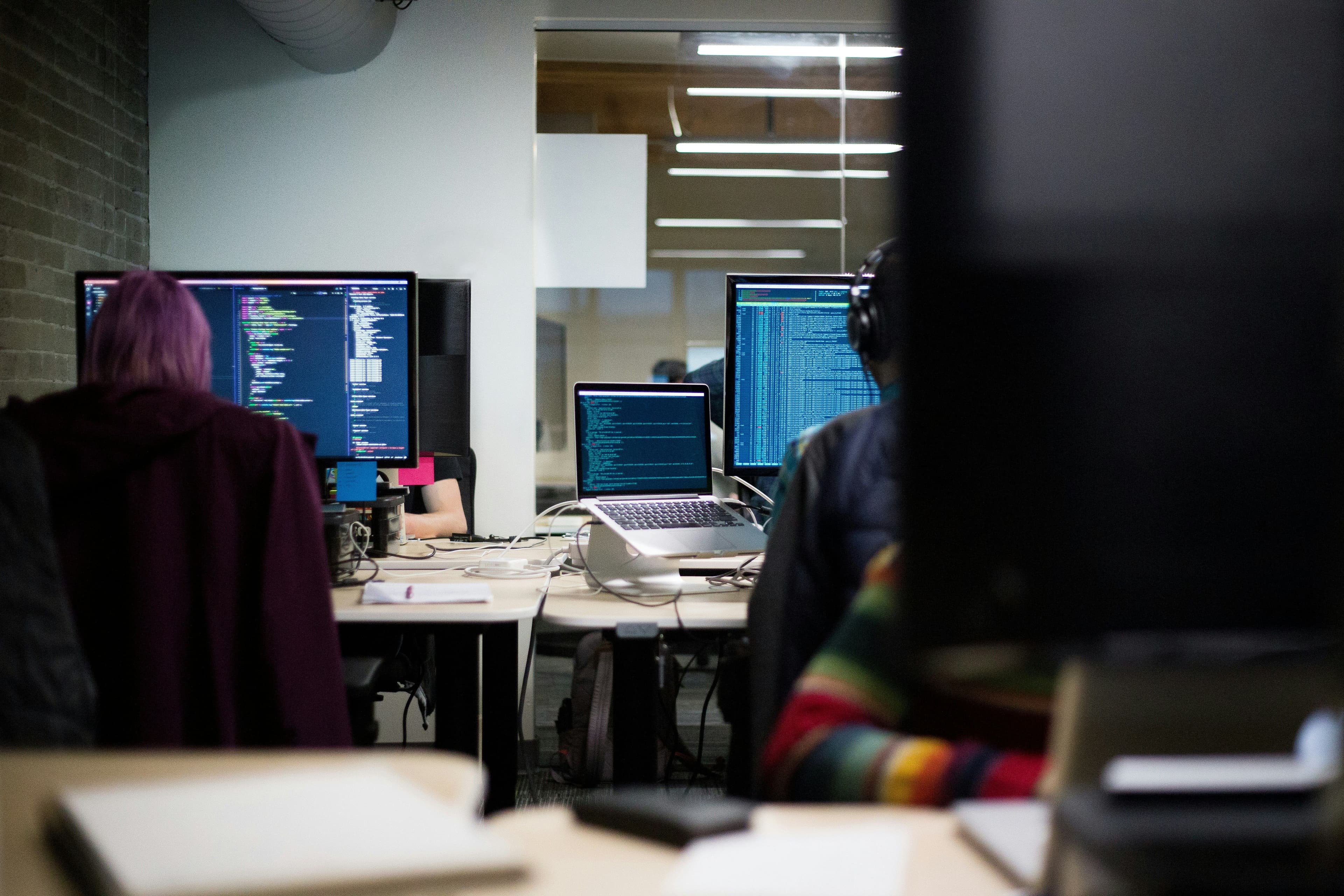 view from behind of multiple people working on a computer desktop 