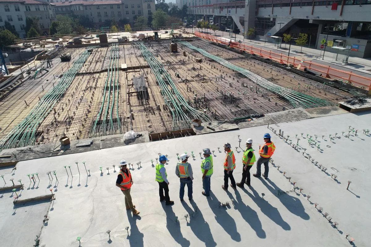 eight people standing on a construction site wearing hard hats and safety vests