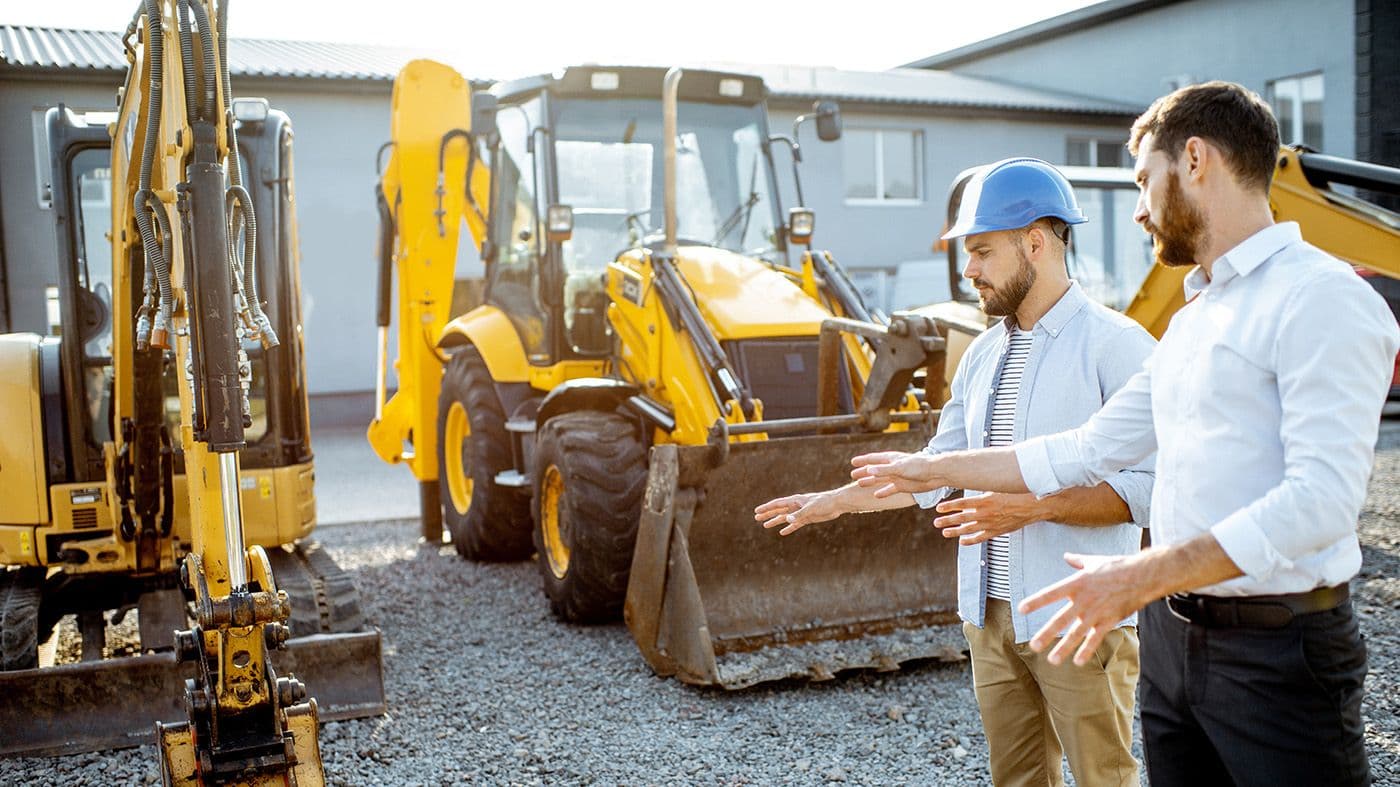 2 men checking out heavy equipment